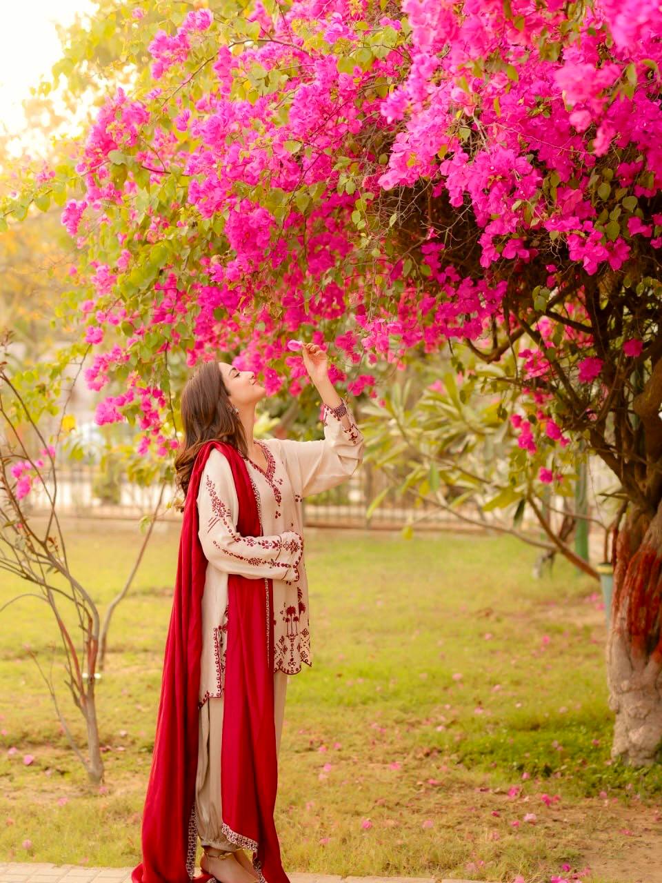 Elegant woman in vibrant attire by tree